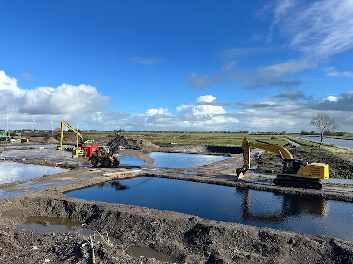 Graafmachines en shovel bij waterbassins voor ontwatering van baggerspecie in Harlingen