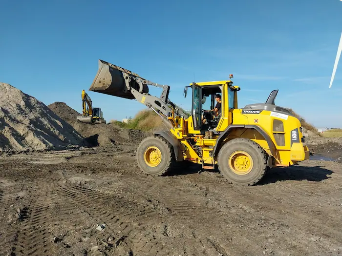 shovel verwerkt grond op locatie met rupskraan op achtergrond